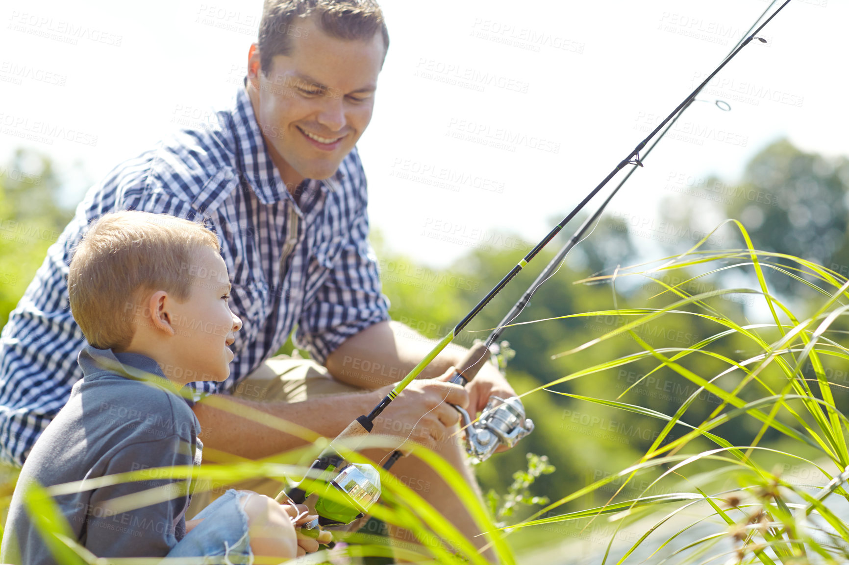 Buy stock photo Father and son sitting together and fishing in the sunlight