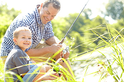 Buy stock photo Cute young boy sitting beside his dad and learning how to fish