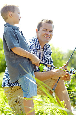 Buy stock photo Young father and son in the sunshine beside a lake holding their fishing rods