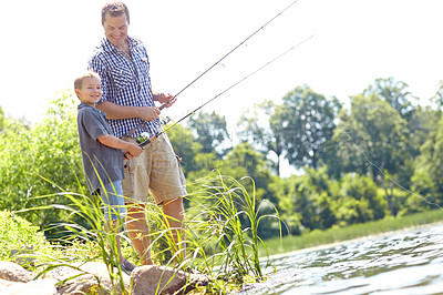 Buy stock photo Father and son standing beside a lake and holding their fishing rods