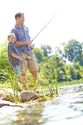 Buy stock photo Cute young boy smiling while fishing by a lake with his dad