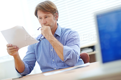 Buy stock photo Head and shoulder shot of an attractive businessman concentrating on a document