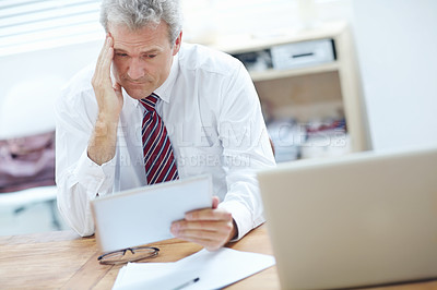 Buy stock photo Overworked business associate looking gloomily at a tablet