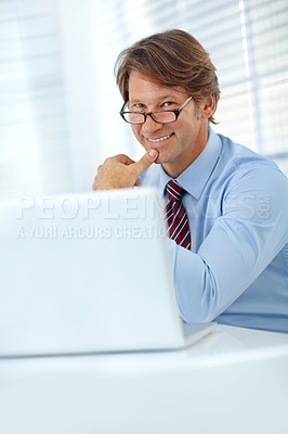Buy stock photo Portrait of a smiling mature businessman working at his laptop