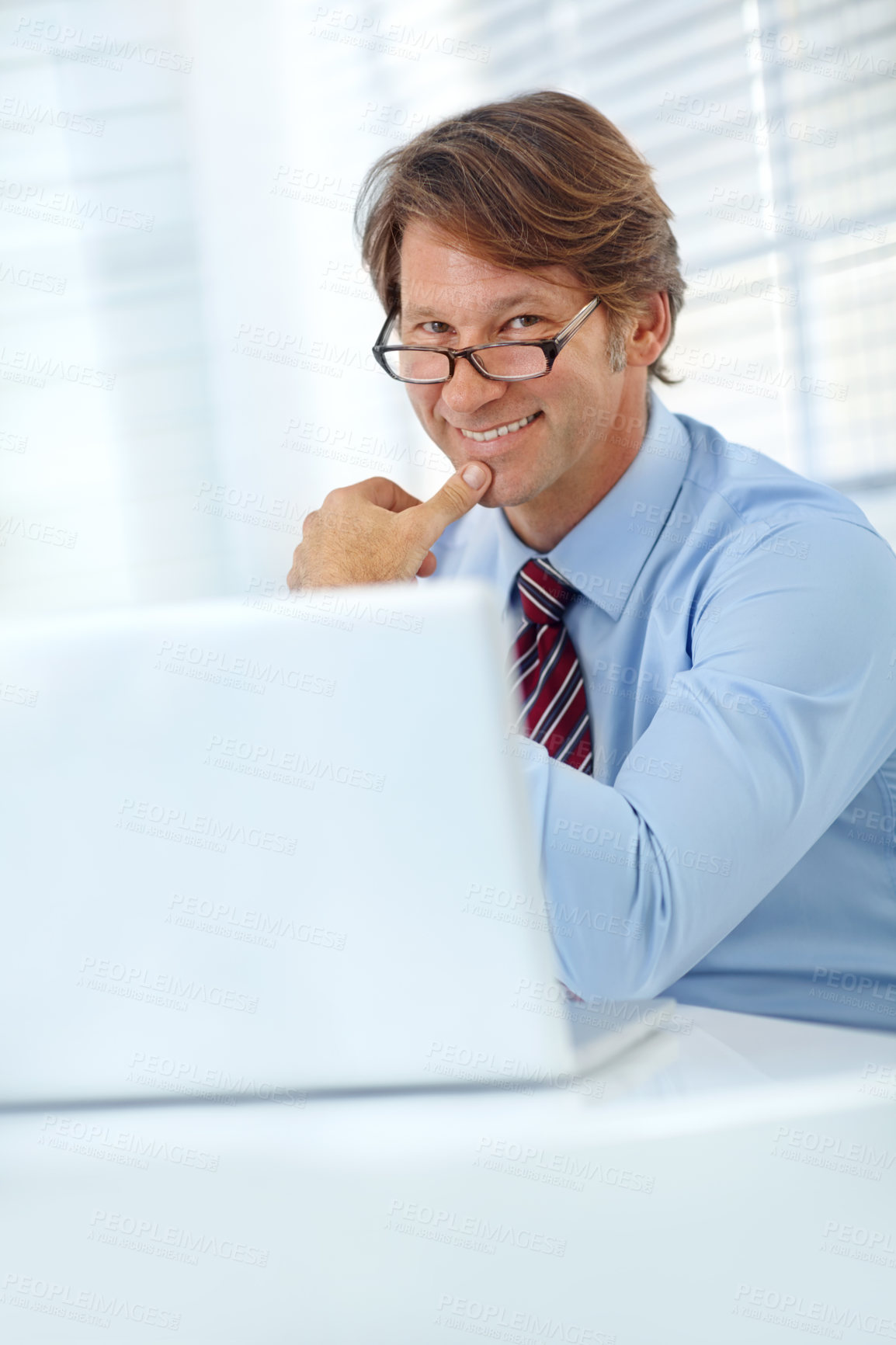 Buy stock photo Portrait of a smiling mature businessman working at his laptop