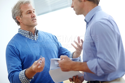 Buy stock photo Cropped shot of two mature businessmen standing in an office and discussing paperwork