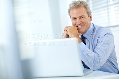 Buy stock photo Portrait of a mature businessman sitting at his desk in front of a laptop