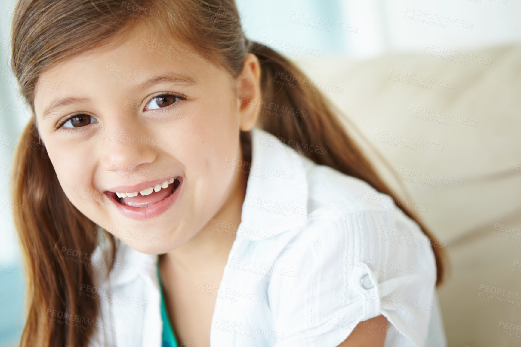 Buy stock photo Girl, laughing and portrait of child on sofa for fun on weekend in living room of house or home. Smile, satisfaction or face of funny kid alone on couch for happiness, comfort and childhood in Spain