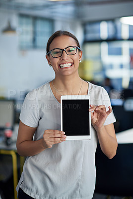 Buy stock photo Friendly young woman in an office space holding up a digital tablet