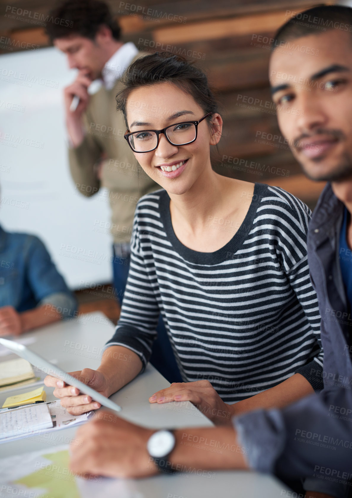 Buy stock photo Portrait of two coworkers sitting at a table in an office using a digital tablet