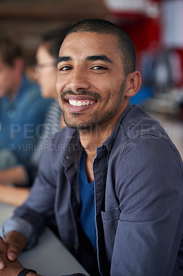 Buy stock photo Portrait of an handsome young man sitting in an office with colleagues in the background
