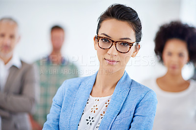 Buy stock photo Young businesswoman looking at the camera with colleagues in the background