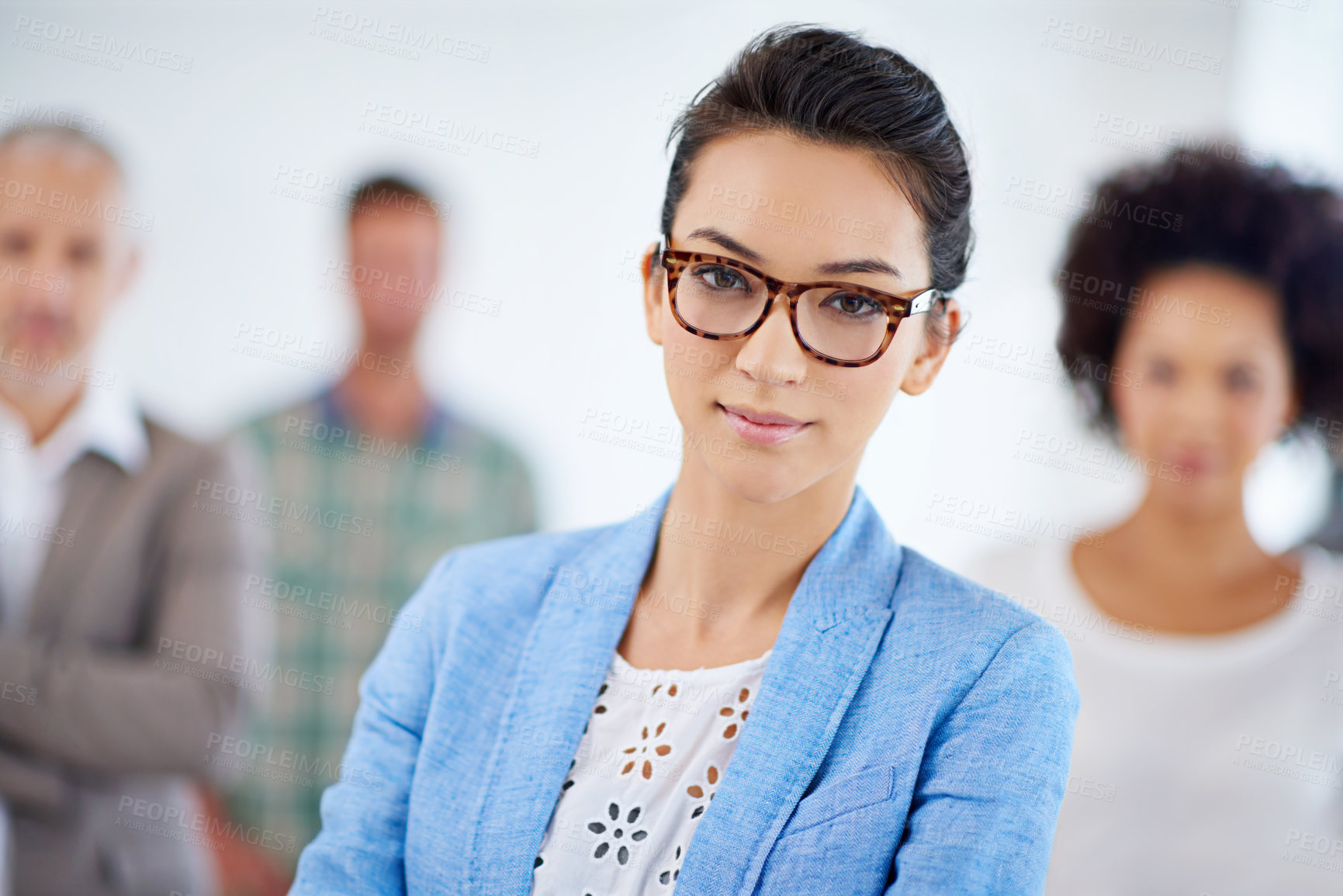 Buy stock photo Young businesswoman looking at the camera with colleagues in the background