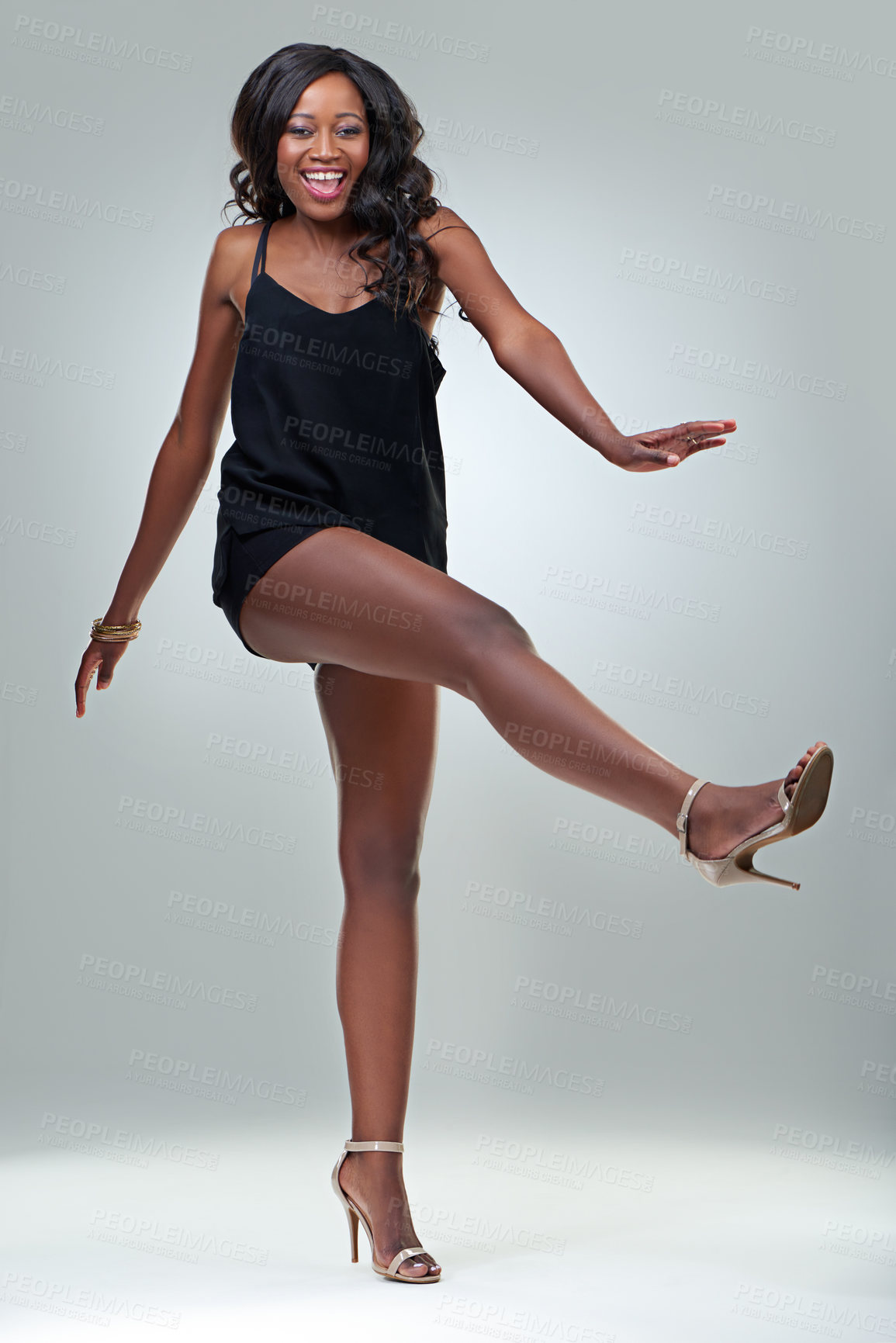 Buy stock photo Studio shot of a beautiful young woman posing in a black dress against a gray background