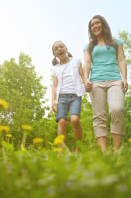 Buy stock photo A mother and daughter holding hands while walking in the outdoors