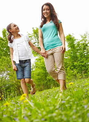 Buy stock photo A mother and daughter holding hands while walking in the outdoors
