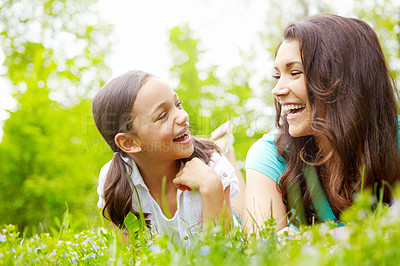 Buy stock photo A mother and daughter looking at each while laughing and lying in a meadow