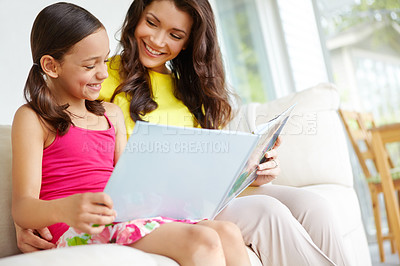 Buy stock photo A mother and daughter reading a book together and sharing a bonding moment