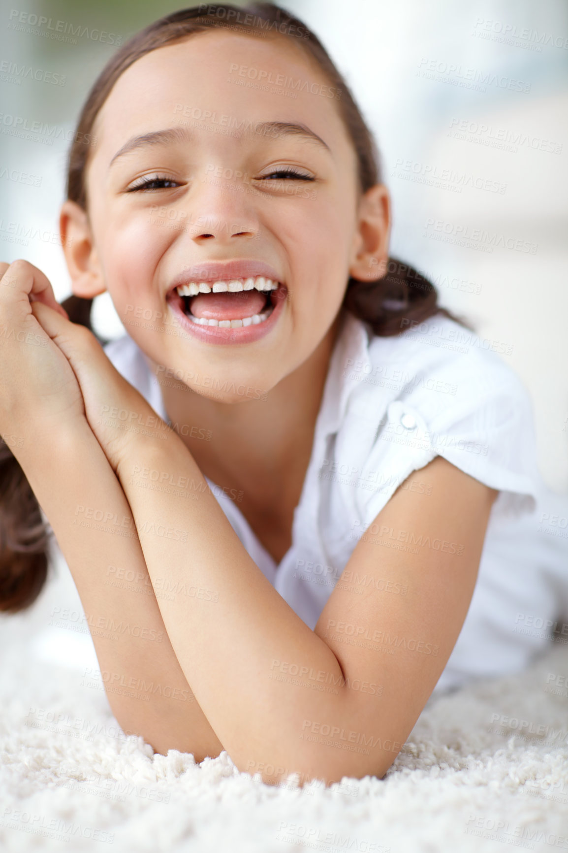 Buy stock photo Carpet, laughing or portrait of girl in house for joy, growth and funny joke in living room of home. Smile, face or silly female kid alone with humor for happiness, satisfaction or childhood in Spain