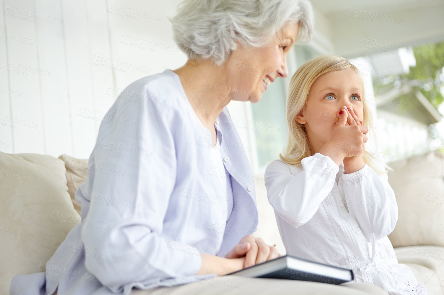 Buy stock photo Girl, elderly grandma and book on sofa in home living room with woman, wow and story for retirement bonding. Happy, senior person and weekend for rest, family and house lounge for memory on couch