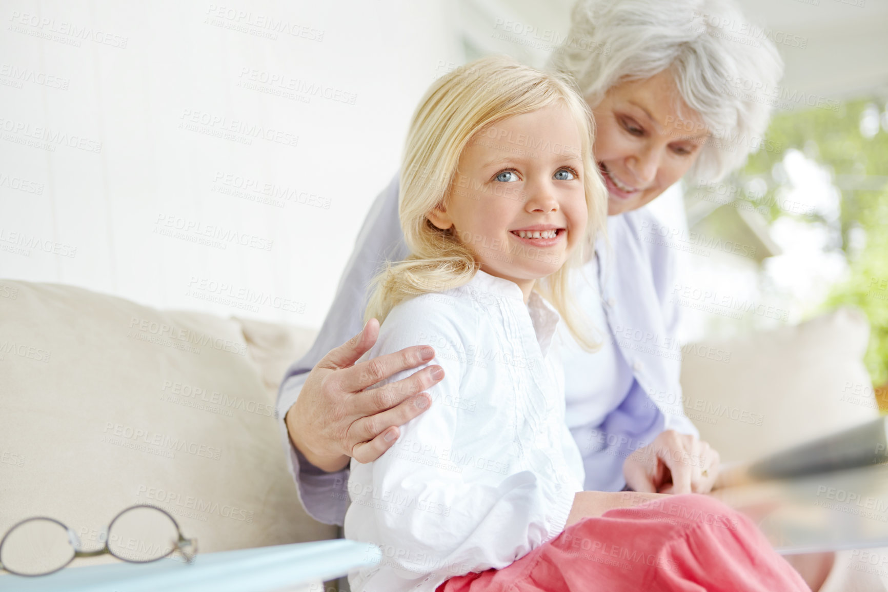 Buy stock photo Girl, elderly grandmother and book in home living room with woman, smile and story for retirement bonding on sofa. Happy, senior person and weekend for rest, family and lounge for memory on couch