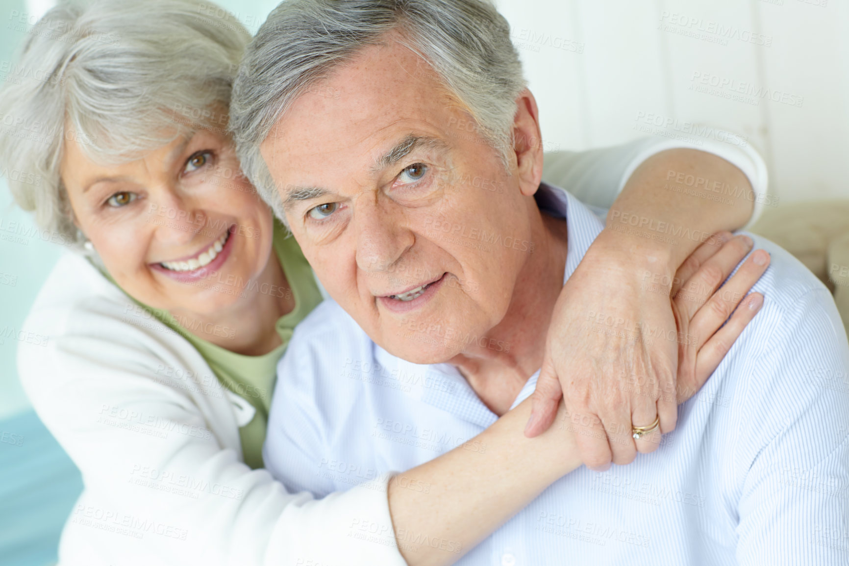 Buy stock photo Hug, portrait and smile of senior couple on sofa in living room of home together for bonding or commitment. Face, love or retirement with old man and woman embracing in apartment for safety or trust