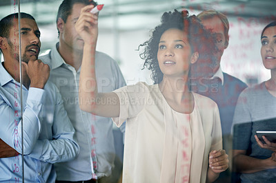 Buy stock photo Shot of a group of creative businesspeople plotting out details on a glass wall
