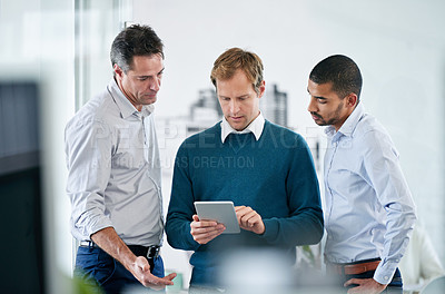 Buy stock photo Shot of a group of colleagues using a digital tablet together in the office