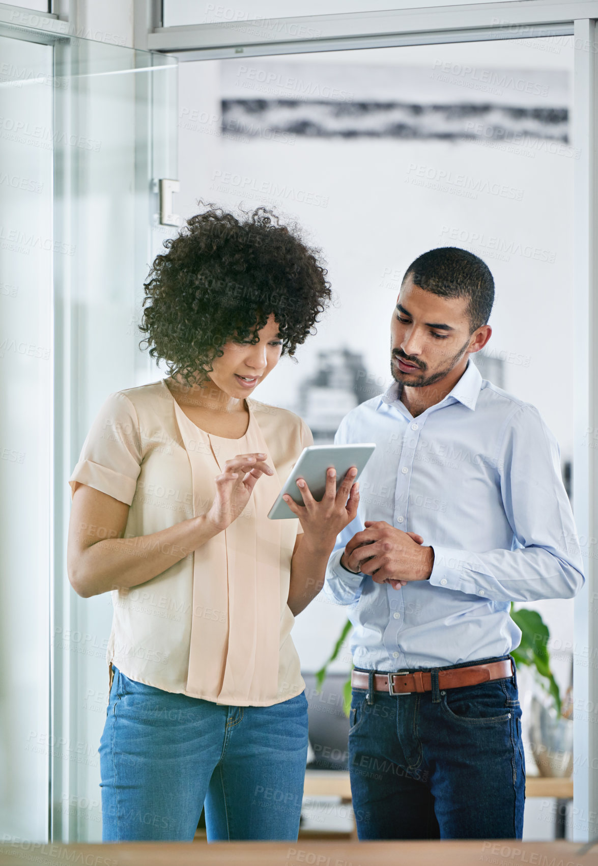 Buy stock photo Shot of two coworkers using a digital tablet together in the office