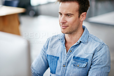 Buy stock photo Shot of a handsome young man working at his desk in an office
