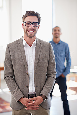 Buy stock photo Portrait of a young man standing in an office with a coworker in the background
