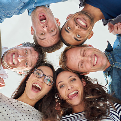 Buy stock photo Low angle shot of excited people putting their heads together