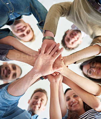 Buy stock photo Low angle shot of a group of co-workers stacking their hands on top of each other 