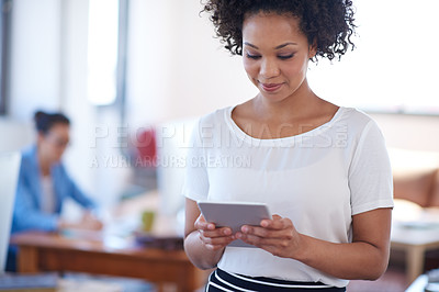 Buy stock photo Cropped shot of an attractive young woman using a digital tablet with a coworker in the background