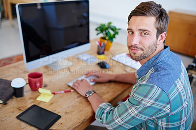 Buy stock photo Handsome young businessman looking up at you while working at his desk