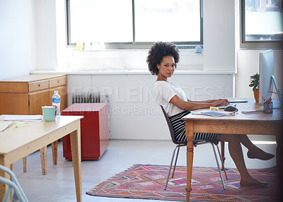 Buy stock photo Young african businesswoman at her desk in an open plan creative office space