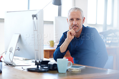 Buy stock photo Portrait of a confident mature man sitting at his desk in a bright office space