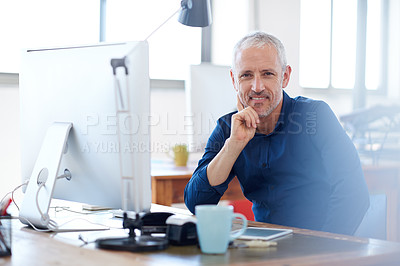 Buy stock photo Mature creative professional looking positively at the camera while sitting at his desk in a bright work space