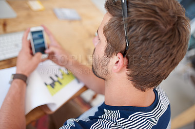 Buy stock photo Top view over the shoulder of a young man looking at information on his mobile phone