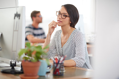 Buy stock photo Young creative professional working at her desk with colleague in the background