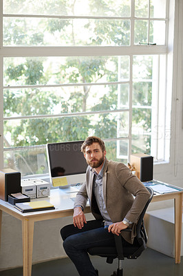 Buy stock photo Shot of handsome male designer looking at the camera while sitting at his desk
