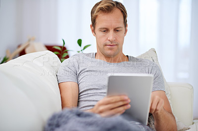 Buy stock photo Man, tablet and ebook reading on couch for morning relaxing or news on digital app, connection or internet. Male person, sofa and online technology or article research in home, apartment or lounge
