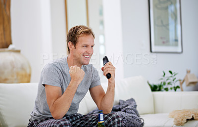 Buy stock photo Shot of a handsome man celebrating while watching a sports match on tv