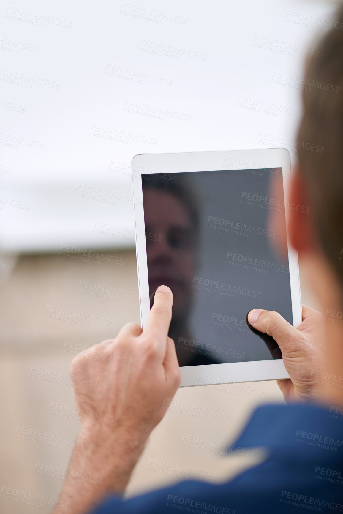Buy stock photo Over the shoulder shot of a man using a digital tablet