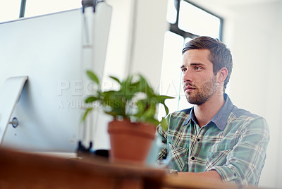 Buy stock photo Shot of a casually-dressed young man at work on a computer