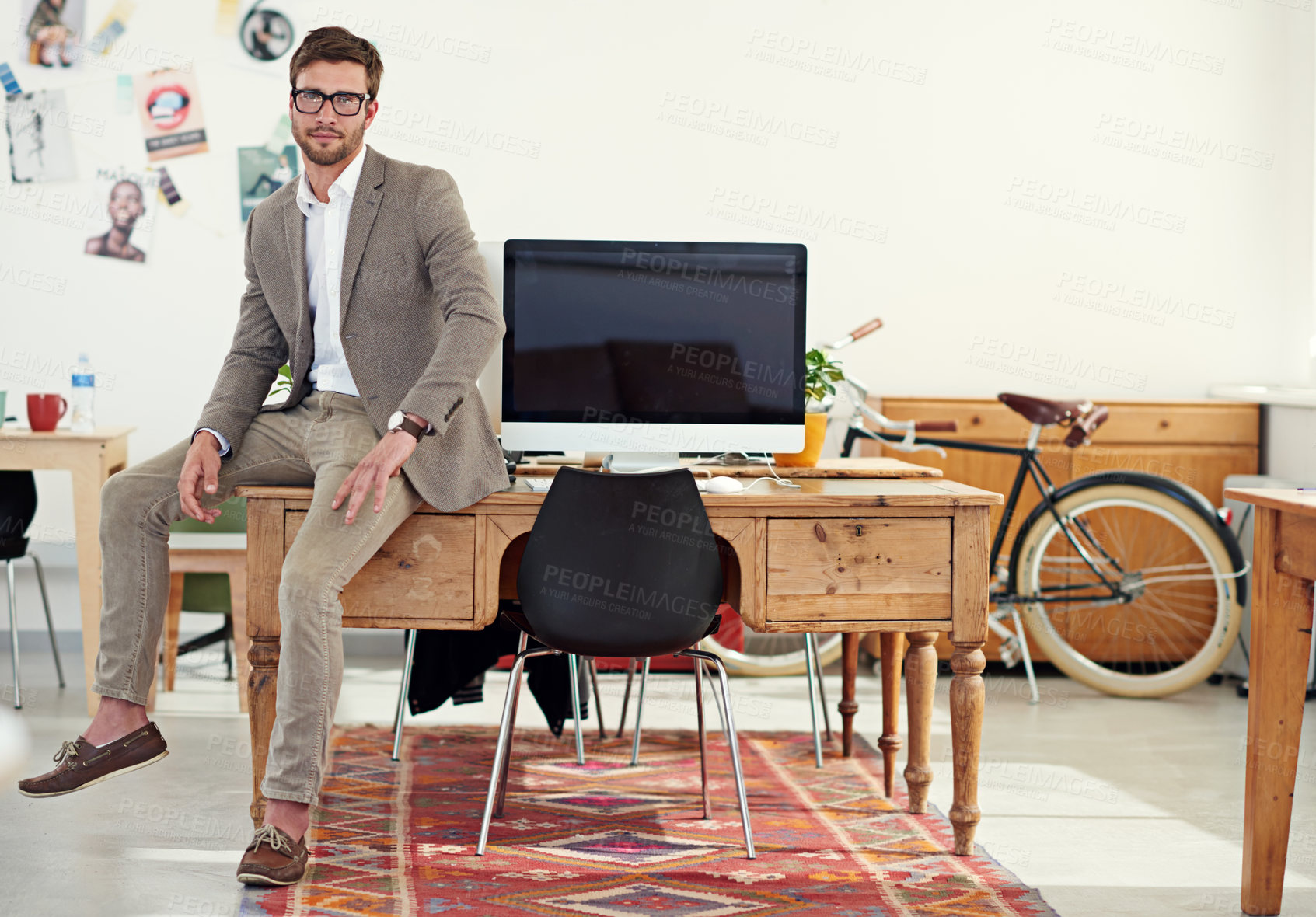 Buy stock photo Portrait of a casually-dressed young man sitting on his desk in an office