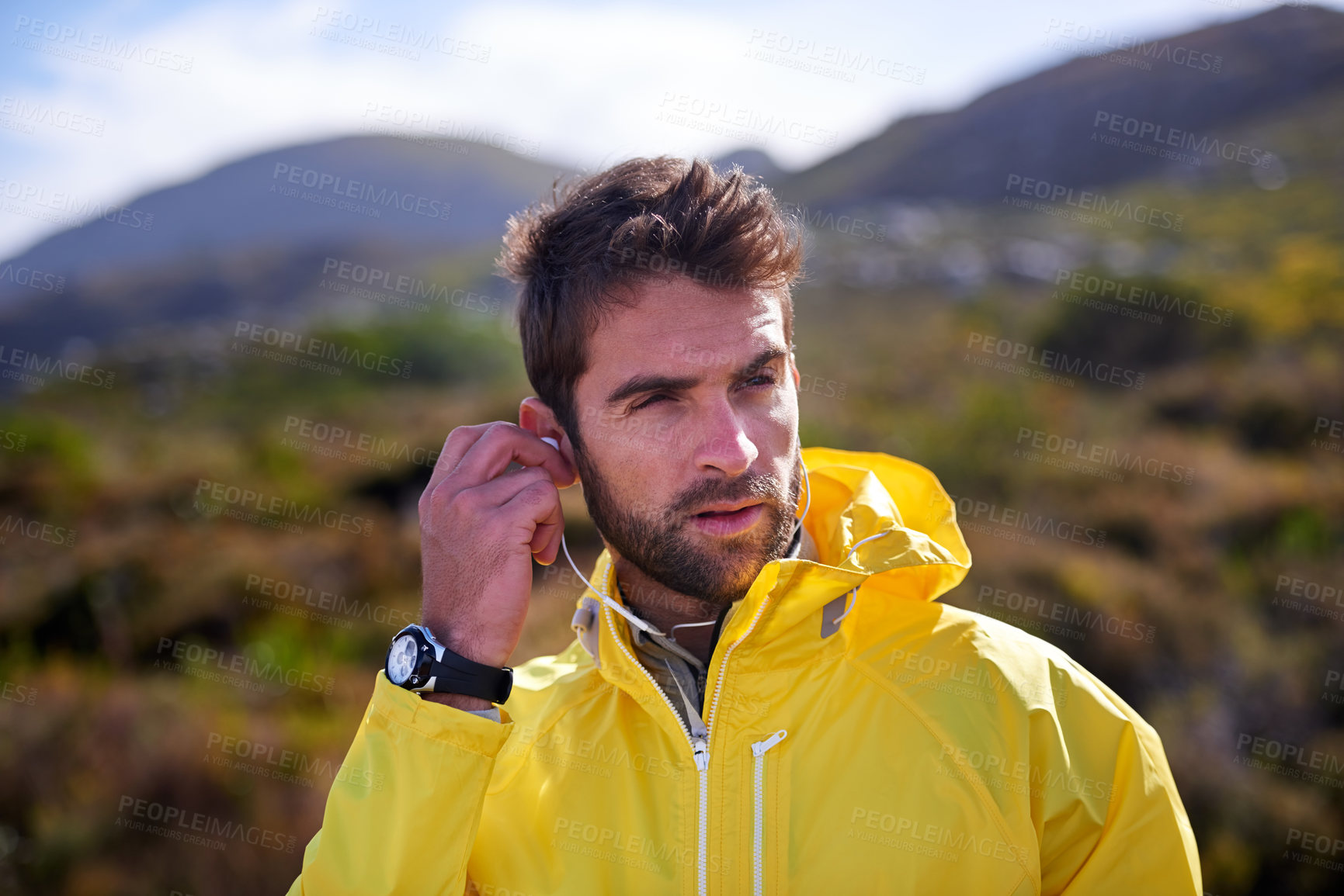 Buy stock photo Earphones, outdoors and man in nature, mountain and flora for exercise or training. Raincoat, music and workout for trail running or adventure hike, podcast and wellness fitness for endurance athlete