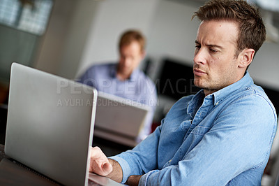 Buy stock photo Shot of a man working on a laptop in an office