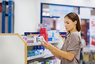 Buy stock photo A young woman buying medicine in a pharmacy -The commercial designs displayed represent a simulation of a real product and have been changed or altered enough by our team of retouching and design specialists so that they don't have any copyright infringements