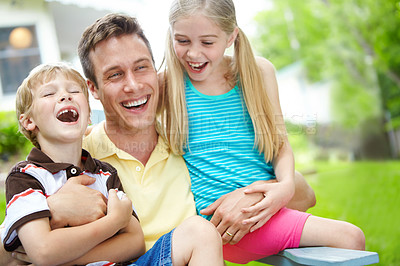 Buy stock photo Handsome young father holding his two children with a happy smile